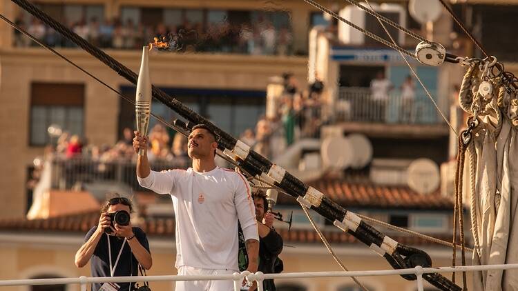 Marseille, France, 2024: French swimmer holds Olympic torch 