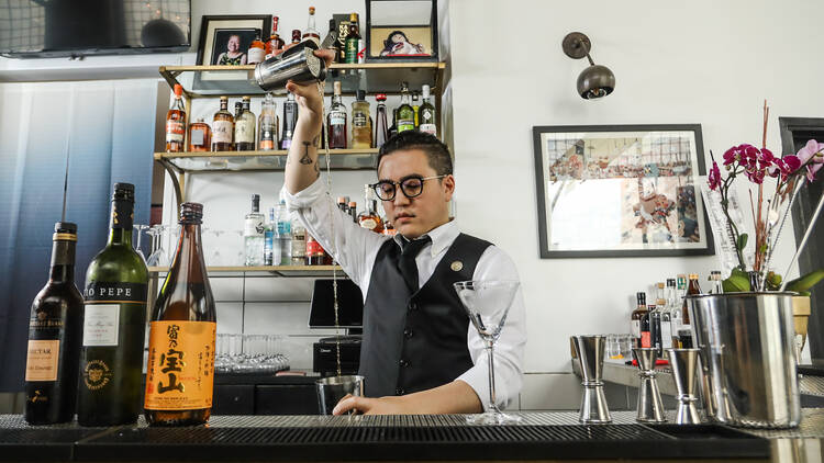 Pham pours a drink behind the counter at Bar Suehiro