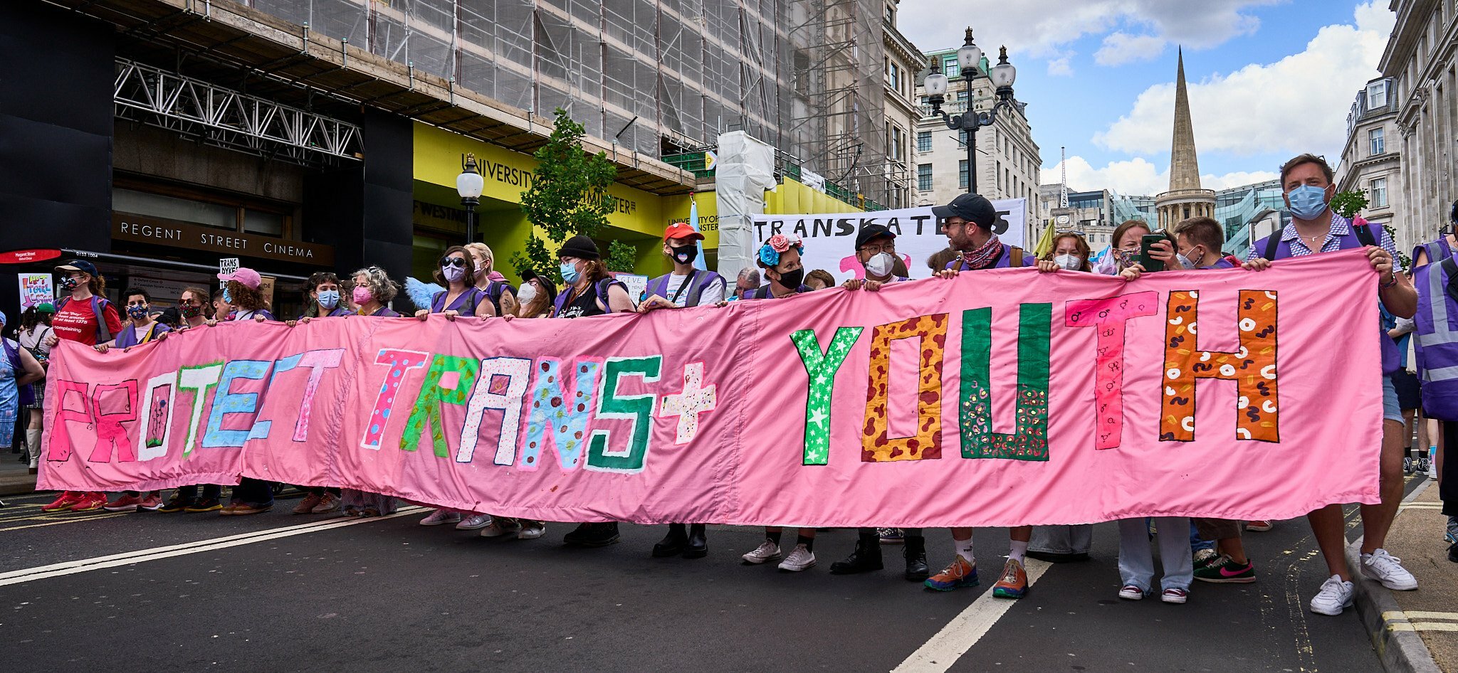 Trans pride marchers holding a banner that says ‘protect trans youth’