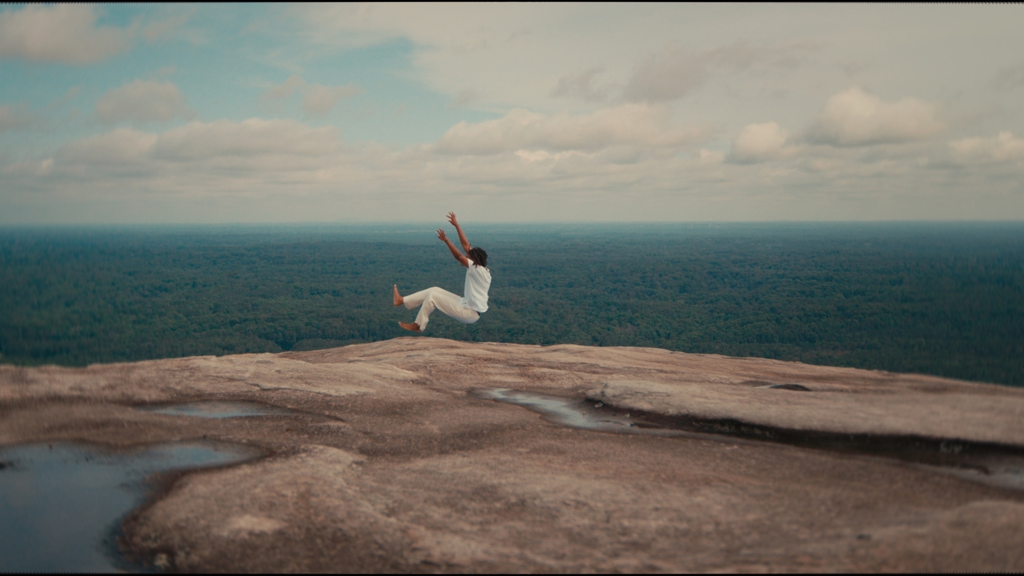 A still from artwork by Le’Andra LeSeur, showing a man near a rock. 