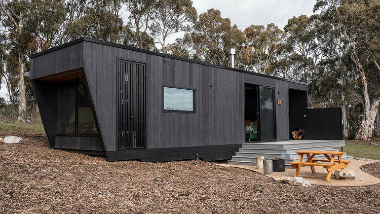 Black tiny home with picnic bench outside