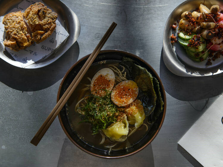 Bowl of ramen, chopsticks, fried chicken and salad.