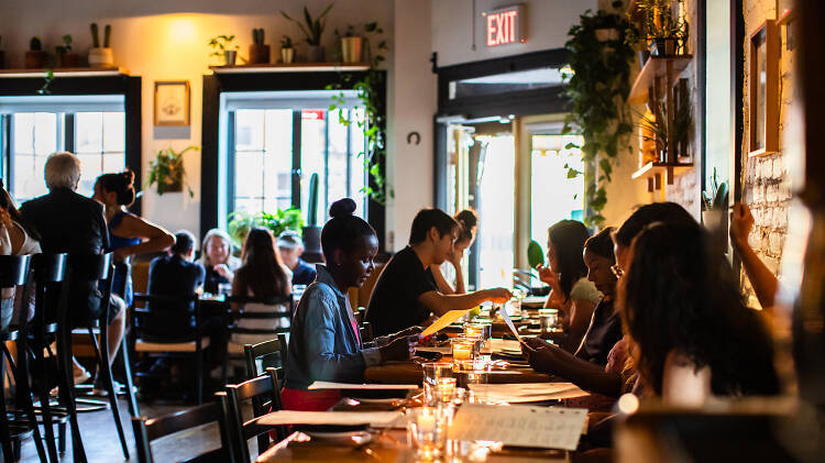 People sitting at long wooden table with candlelights