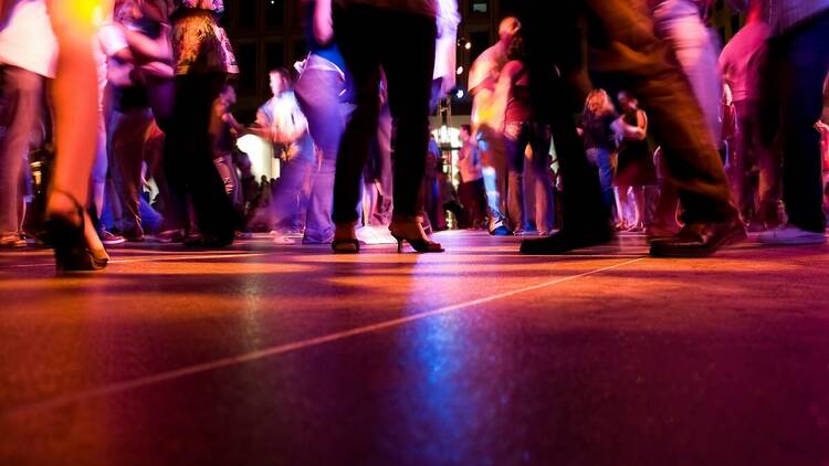 A low shot of the dance floor with people dancing under the colorful lights