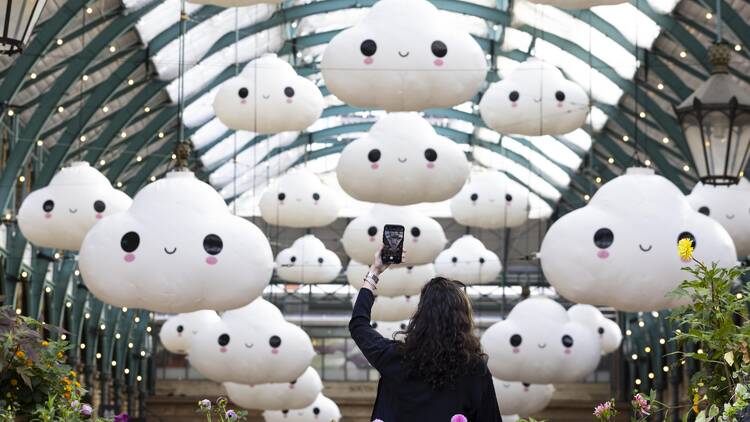 A woman taking a picture of large cloud sculptures