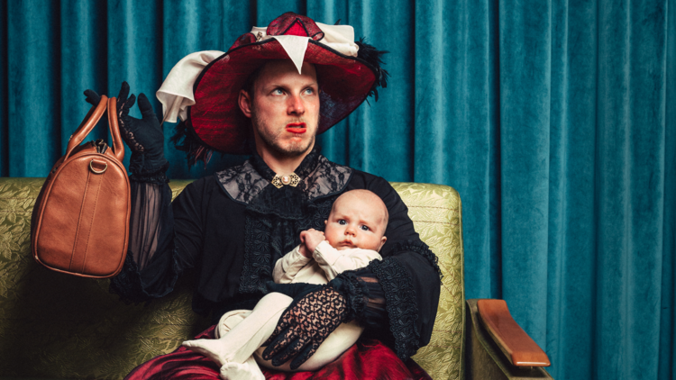 A person wearing old fashioned dress holds a baby