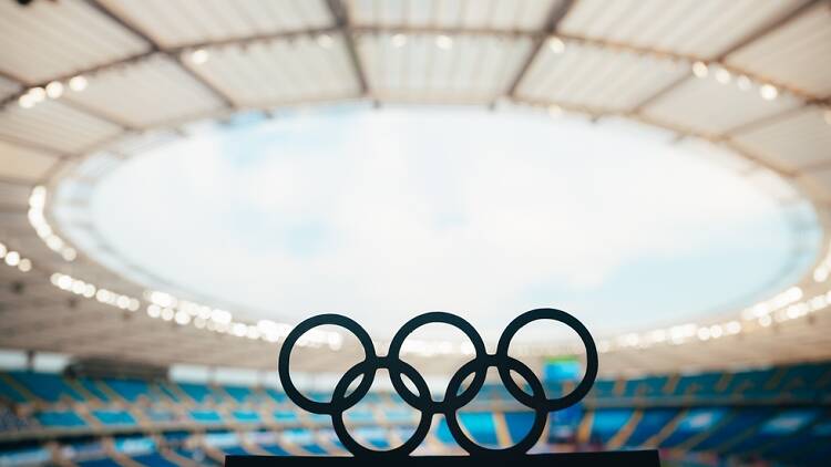 Olympic rings silhouetted against stadium in Paris