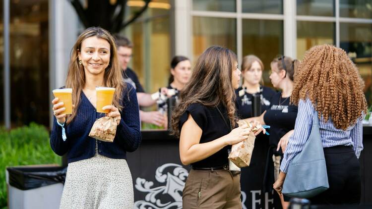 A woman carries two beers from the bar at Tree House Brewing Co. beer garden Prudential Center