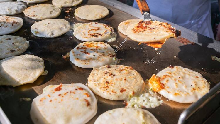 Pupusas being prepared on a hot gas griddle