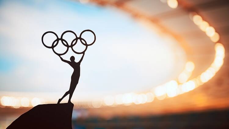 Olympic rings in silhouette with stadium in the background