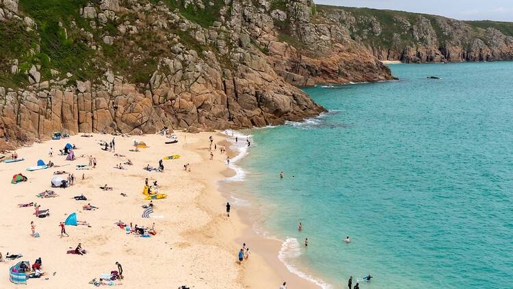 Holidaymakers in the sun on Porthcurno Beach in Cornwall. 