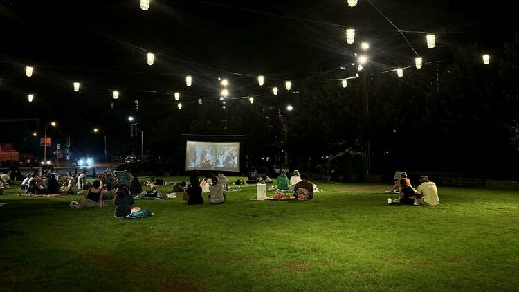 People watch an outdoor movie at Time Out Market on the lawn at 401 Park Fenway 