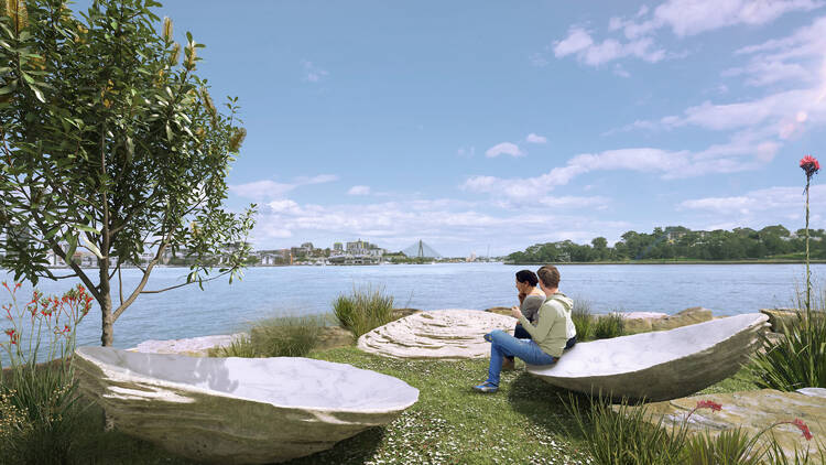 Two people sitting on an oyster sculpture by Sydney Harbour