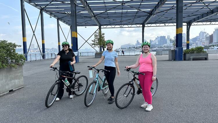 Three women standing next to bikes.