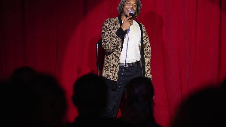 Performer Justin Catchens on stage in a leopard-print jacket.