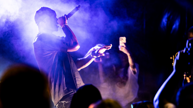 A performer on stage back lit by neon lights