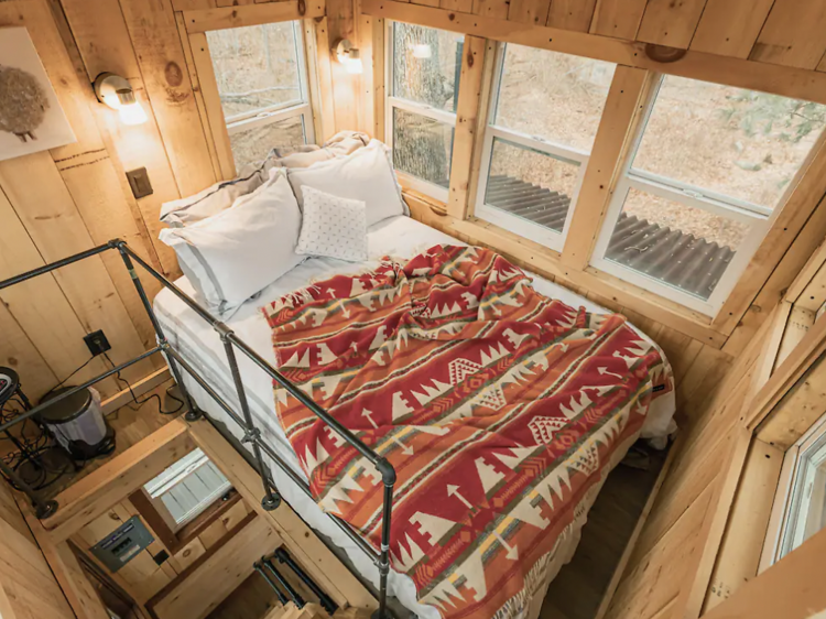 Interior of treehouse Airbnb rental with a mezzanine bedroom.