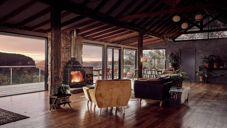 A cabin with a fireplace, with windows looking out over the Blue Mountains