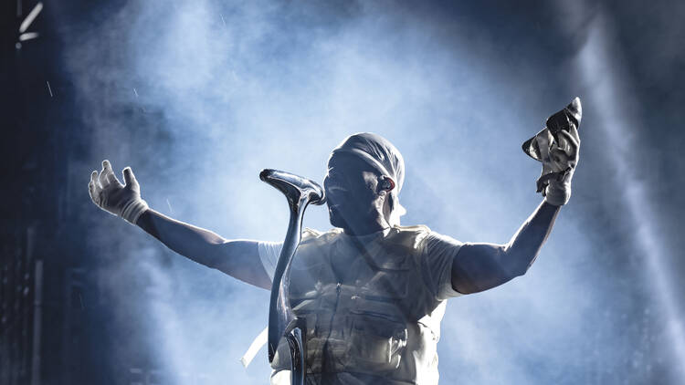 The Weeknd performing with arms outstretched on stage.