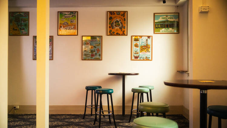 A vintage looking pub with bar stools and framed pictures on the wall.