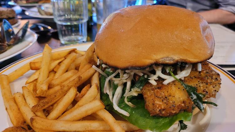 A fish burger on a plate with fries