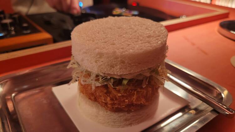 A round deep-fried prawn patty sandwich