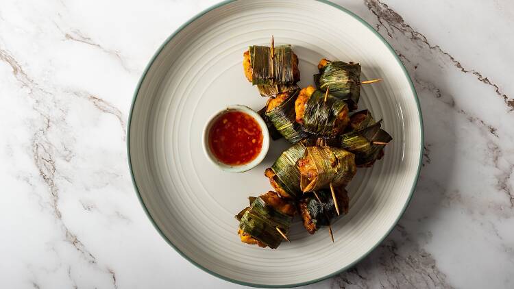 Homemade pandan fried chicken on a white plate with a red dipping sauce