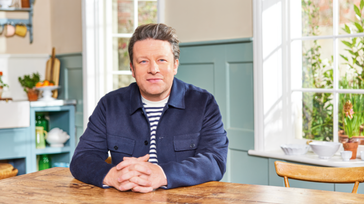 Jamie Oliver sitting at a table.