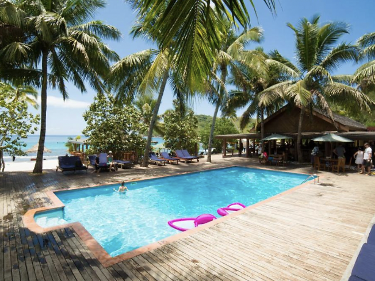 Outdoor pool with pink floats and a wooden deck. 