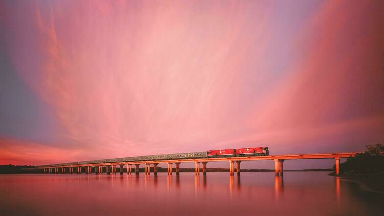 Train travelling over bridge at sunset