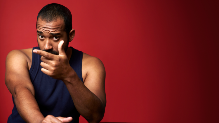 Actor holds a hand in front of his face while looking at the camera