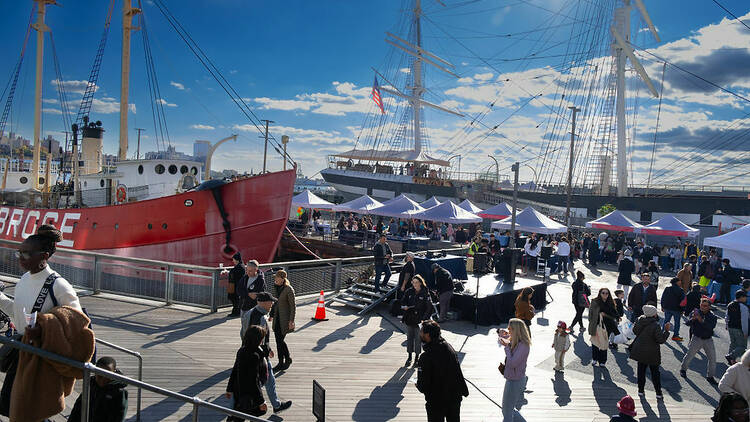 Seaport with a big red boat in the water and white tents