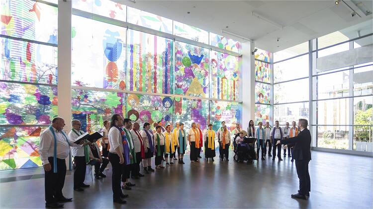 Choir performing in hall with glass art in background