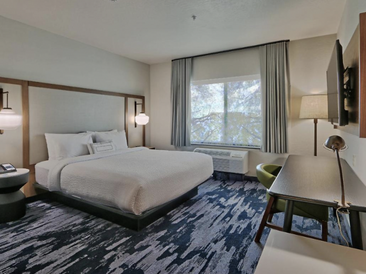 Spacious room with blue carpet, a large bed, and desk.