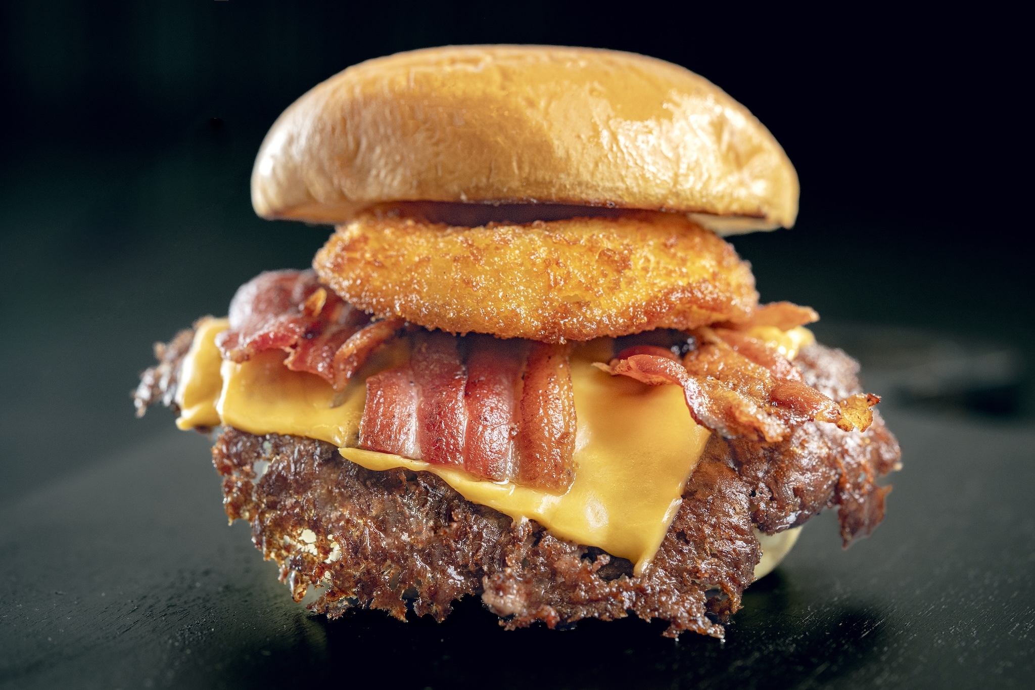 Burger with a fried onion ring, bacon and cheese