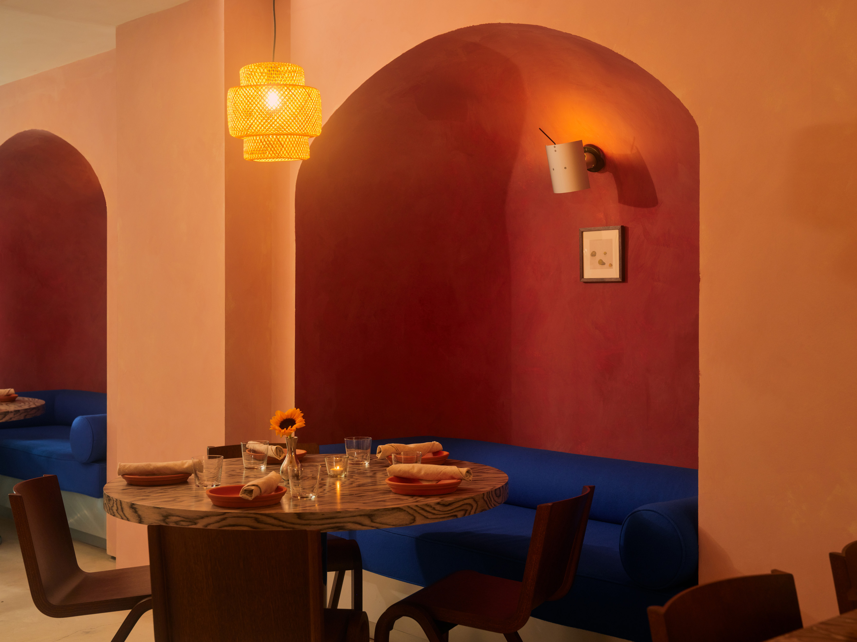 Blue booths in alcloves, marble tables and a pink colored wall at Comida Corrida