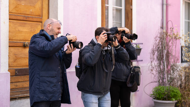 Three people taking street photographs with professional cameras 