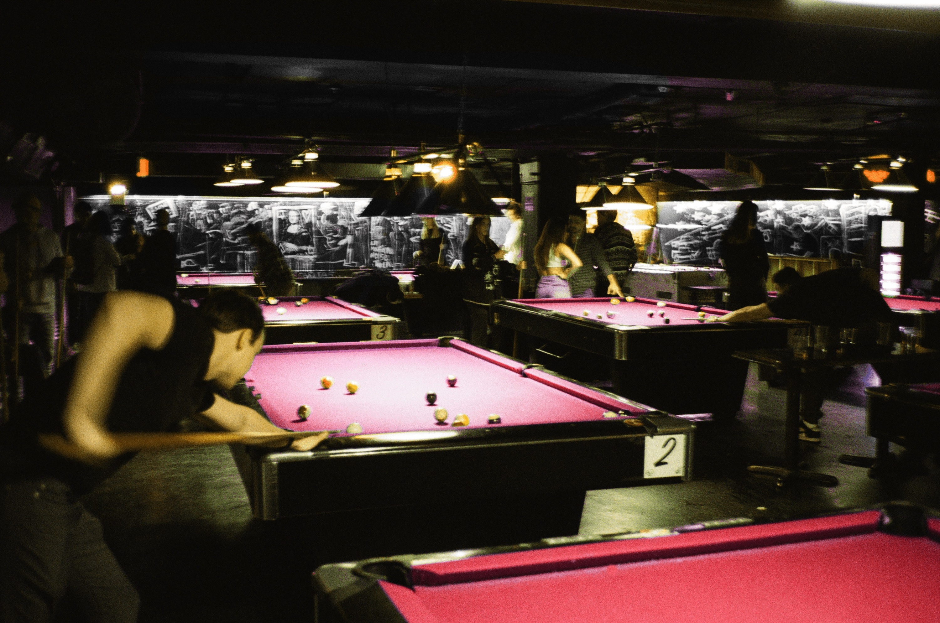 People playing pool on red pool tables