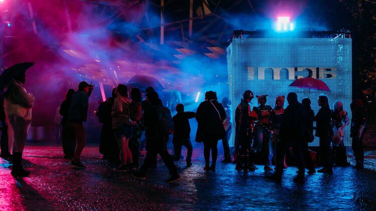 A group of people silhouetted against colourful lighting. 