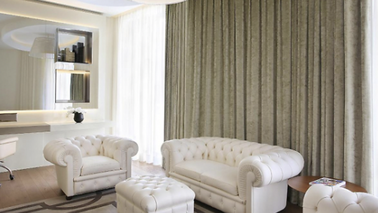 Suite with white leather armchairs, draped curtains and a mirror