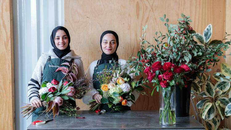 Two Palestinian women holding bouquets of flowers.