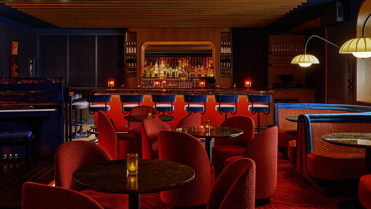 Interior of So & So’s Piano Bar with wooden beams, red seating and red banquette booths