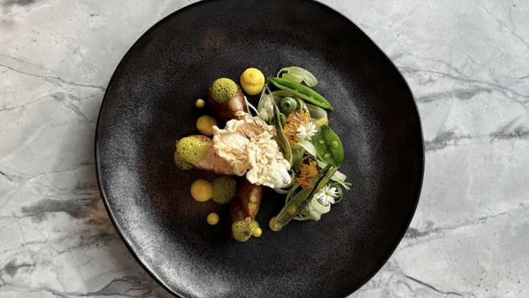 A black plate of food on a grey marble tabletop.