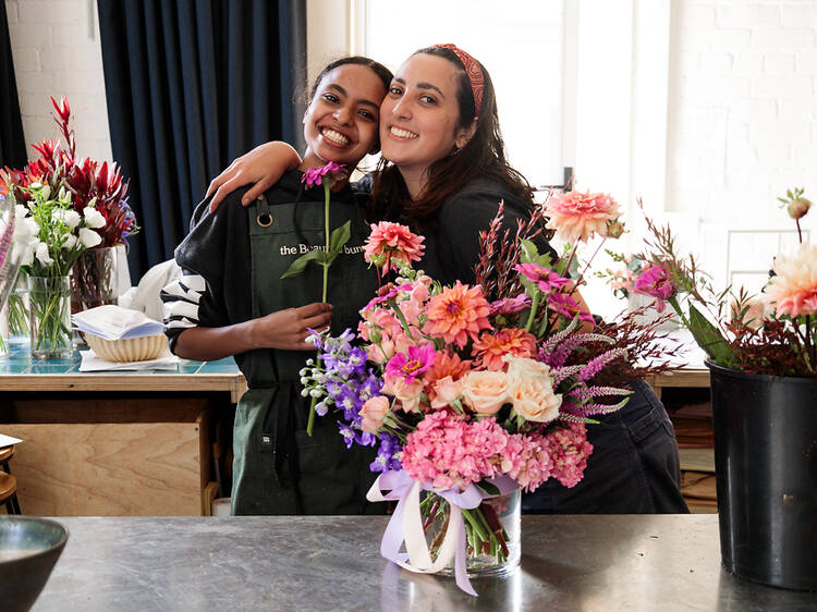 Two people hugging next to a large bouquet of flowers.