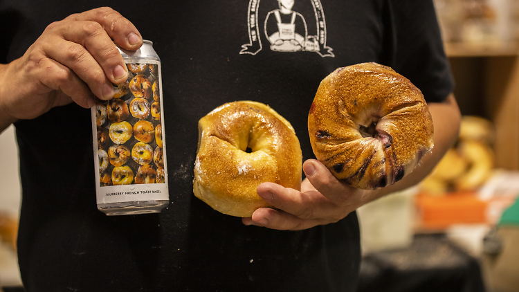 Person holding two bagels and a can of beer