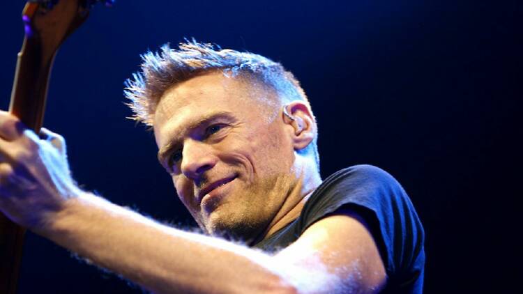 Bryan Adams playing the guitar on stage