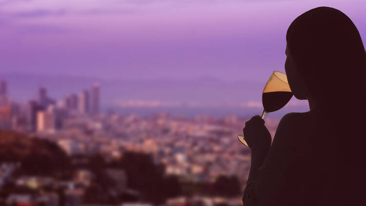 woman drinking wine with San Francisco skyline in background