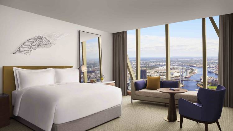 A hotel room with a large bed and views of a harbour. 