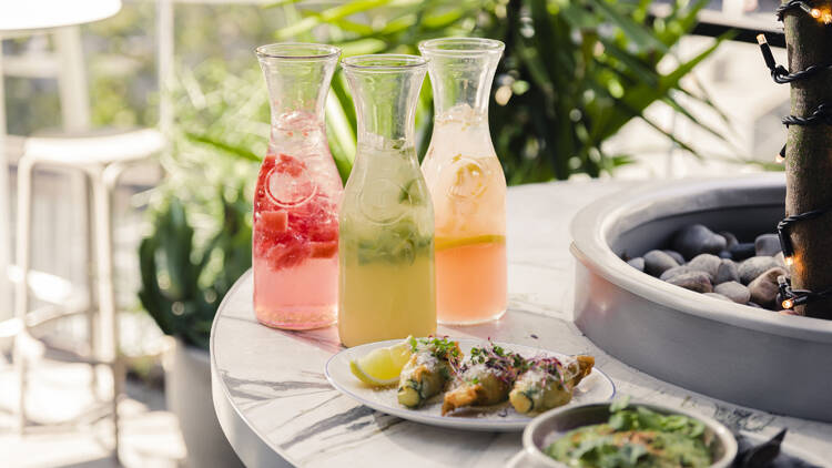 Three jugs of cocktails on a table outdoors