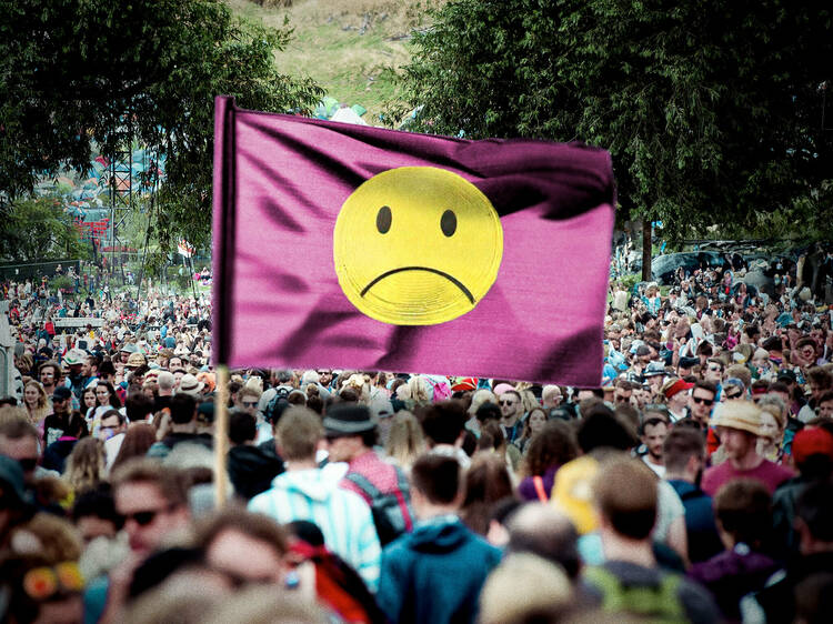 A massive festival crowd and a flag with a sad face 